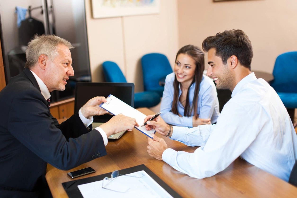 A man handing over papers to two people.